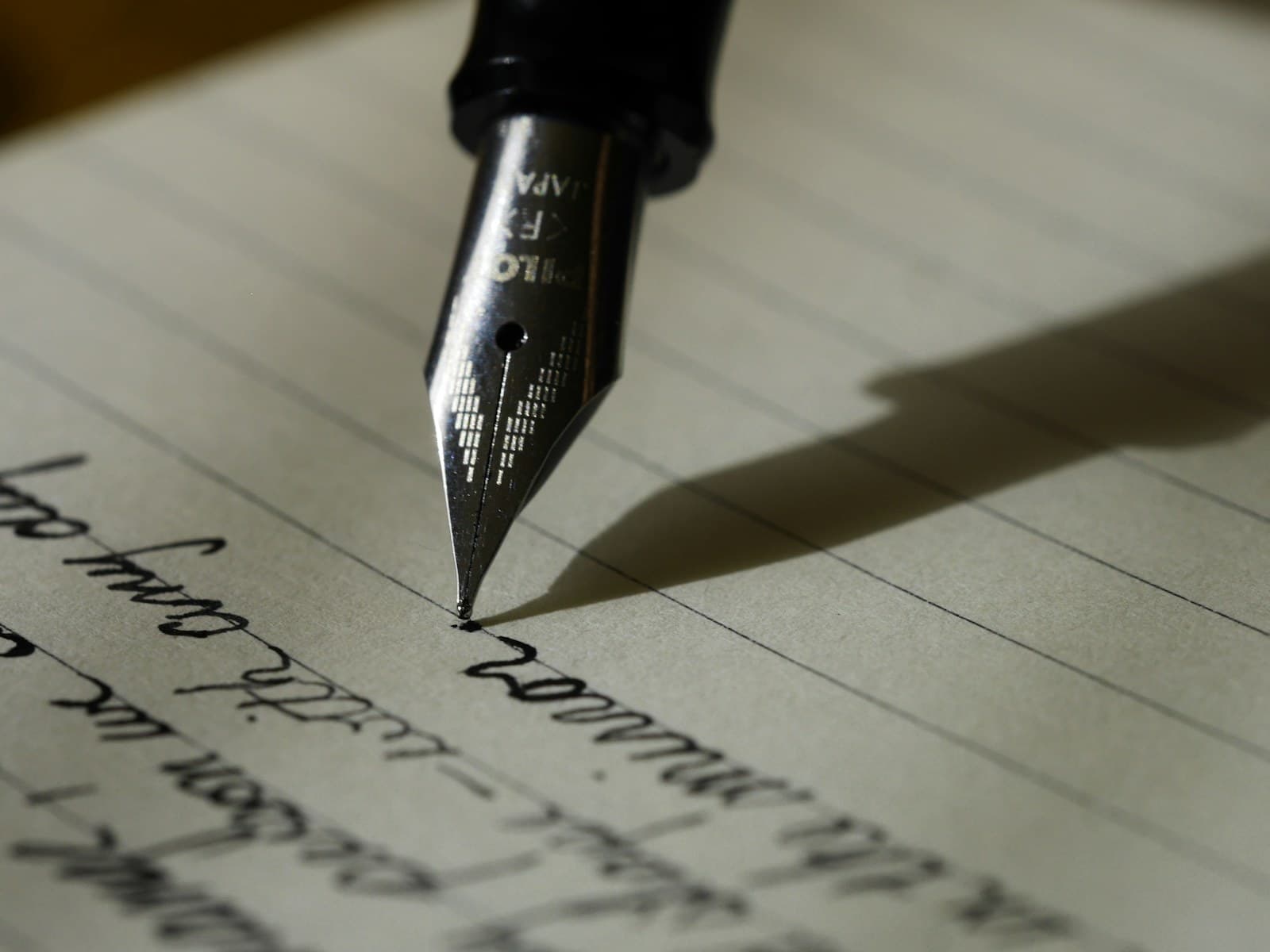 A fountain pen writing on a page in warm light